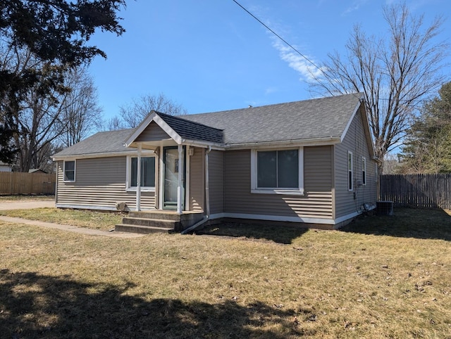 view of front of property with roof with shingles, a front yard, and fence