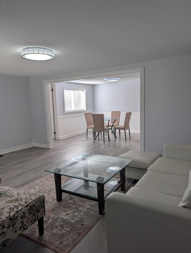 living room featuring a wainscoted wall, a textured ceiling, and wood finished floors