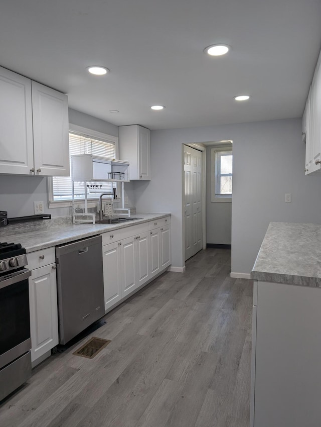 kitchen with white cabinets, light wood-style floors, and stainless steel appliances