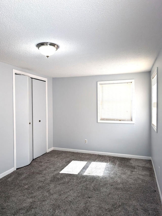 unfurnished bedroom with carpet flooring, baseboards, a closet, and a textured ceiling