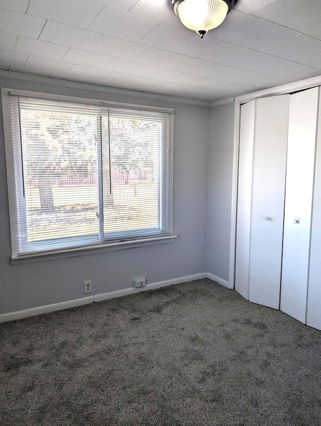 unfurnished bedroom with a closet, carpet flooring, and baseboards