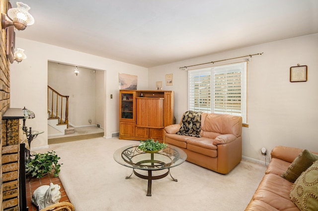 carpeted living area with stairs and baseboards