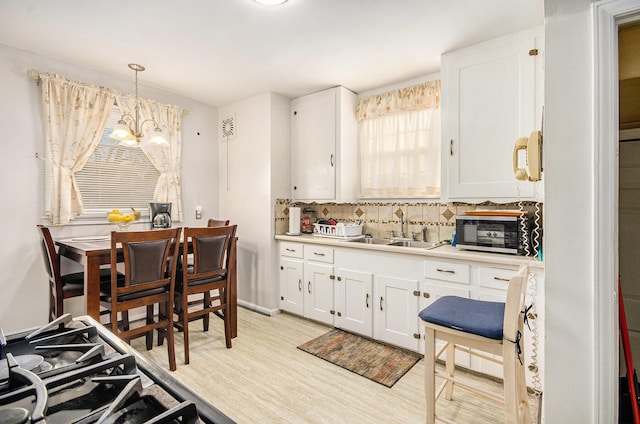 kitchen with a toaster, tasteful backsplash, light wood finished floors, and a sink