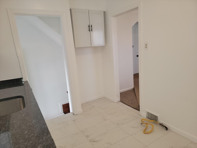 unfurnished dining area featuring visible vents, baseboards, marble finish floor, and a sink