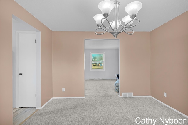 unfurnished dining area with a chandelier, visible vents, carpet, and baseboards