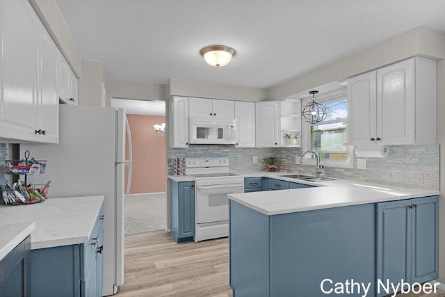 kitchen with blue cabinets, white appliances, a notable chandelier, and a sink