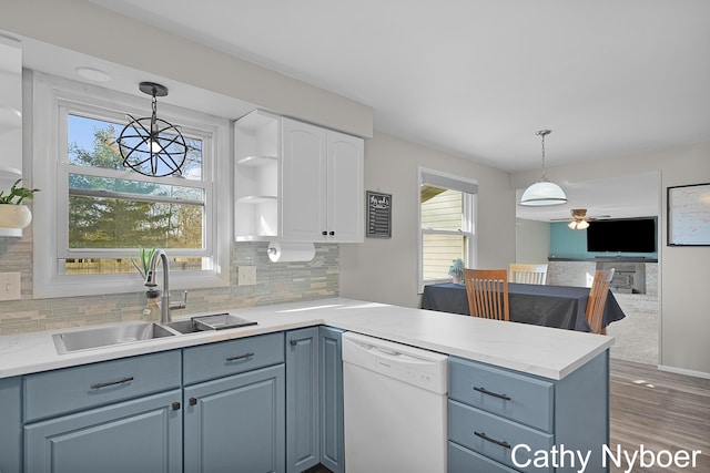 kitchen with open shelves, a peninsula, plenty of natural light, a sink, and dishwasher