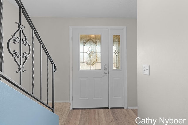 foyer entrance with stairs, light wood-type flooring, and baseboards