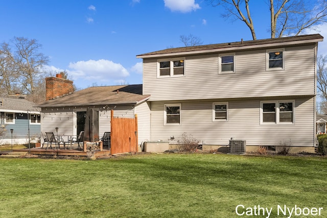 rear view of property featuring a yard, central AC unit, a deck, and a chimney