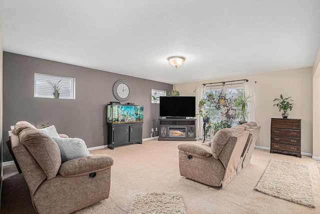 living room with baseboards, light carpet, and a glass covered fireplace