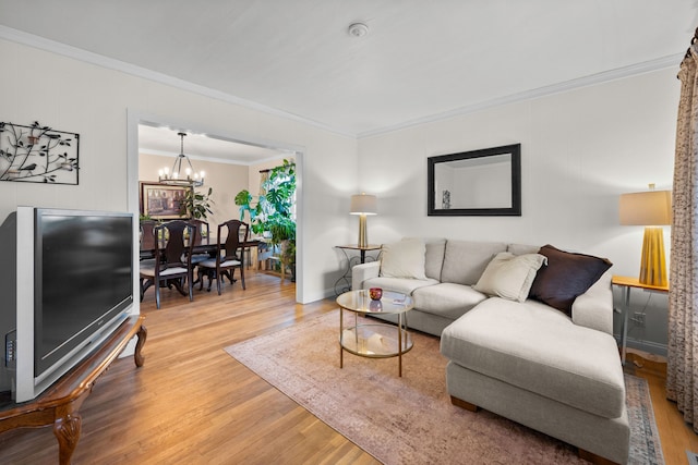 living area with ornamental molding, baseboards, light wood finished floors, and a chandelier