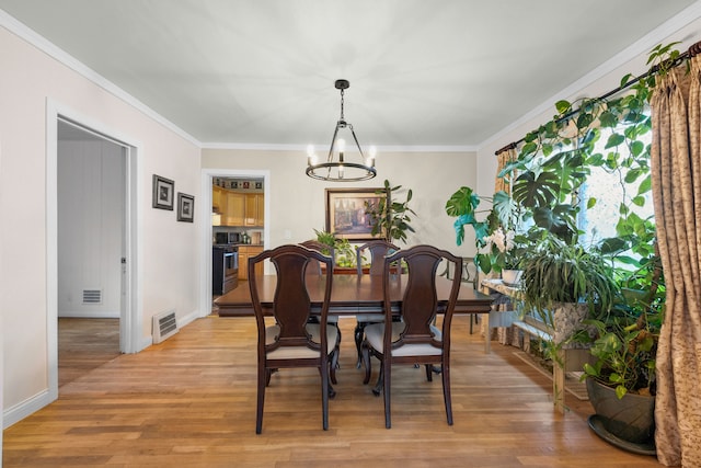 dining area featuring light wood finished floors, visible vents, baseboards, a chandelier, and ornamental molding