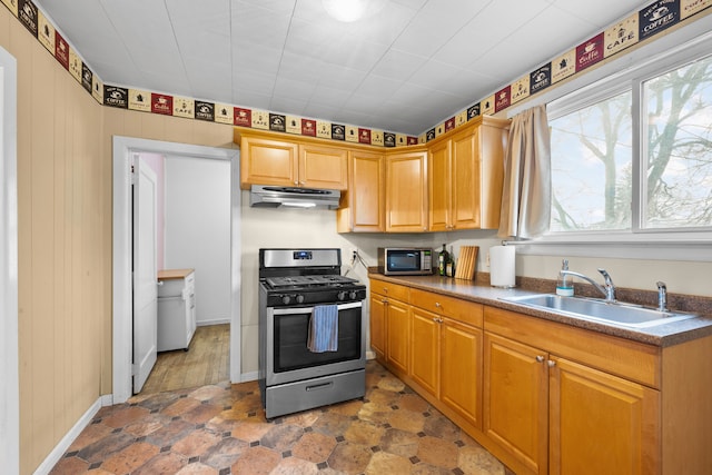 kitchen featuring a sink, dark countertops, appliances with stainless steel finishes, baseboards, and extractor fan