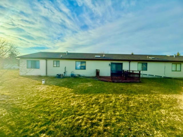 rear view of property with a deck, a yard, and fence