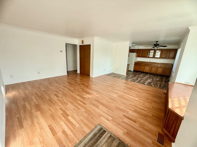 unfurnished living room featuring light wood-style flooring, a ceiling fan, and ornamental molding