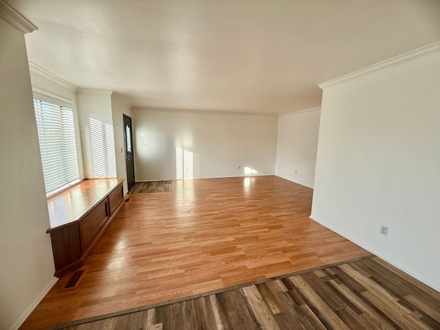 empty room with visible vents, light wood-style flooring, and crown molding