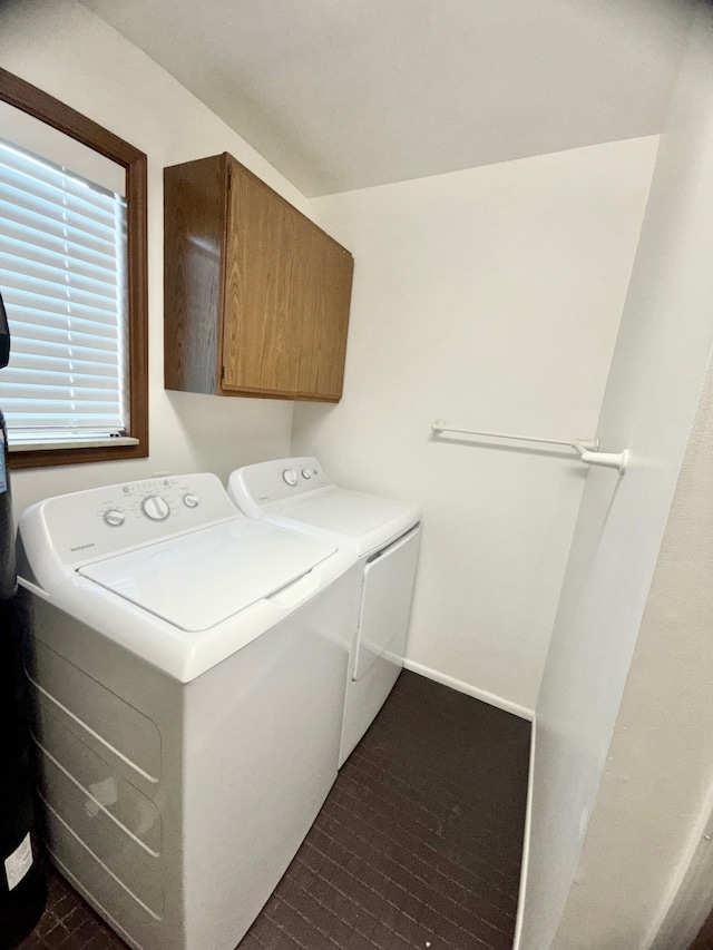 clothes washing area featuring washing machine and dryer, cabinet space, and baseboards