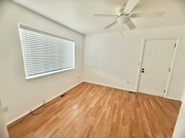 empty room featuring light wood finished floors, visible vents, ceiling fan, and baseboards