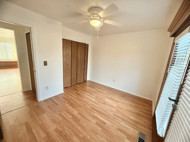 unfurnished bedroom with visible vents, a closet, light wood finished floors, baseboards, and ceiling fan