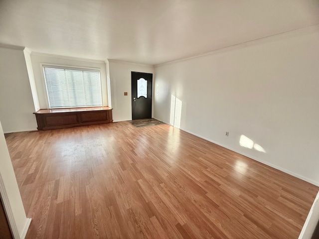 entryway with crown molding, baseboards, and light wood finished floors