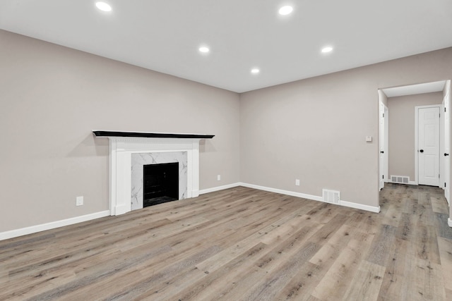 unfurnished living room with recessed lighting, visible vents, wood finished floors, and a fireplace