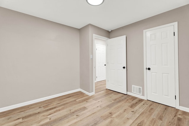 unfurnished bedroom with visible vents, light wood-style floors, and baseboards