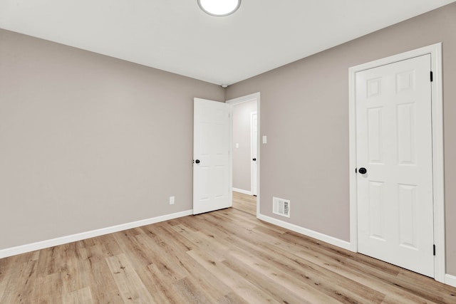 unfurnished bedroom with visible vents, light wood-style flooring, and baseboards