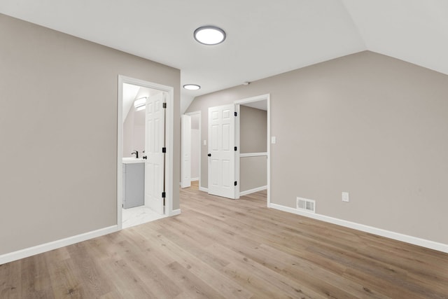 spare room with visible vents, light wood-style flooring, baseboards, and vaulted ceiling