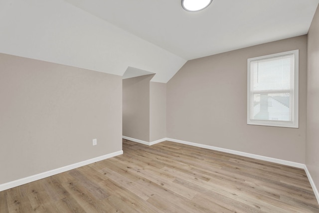 bonus room featuring light wood finished floors, baseboards, and vaulted ceiling