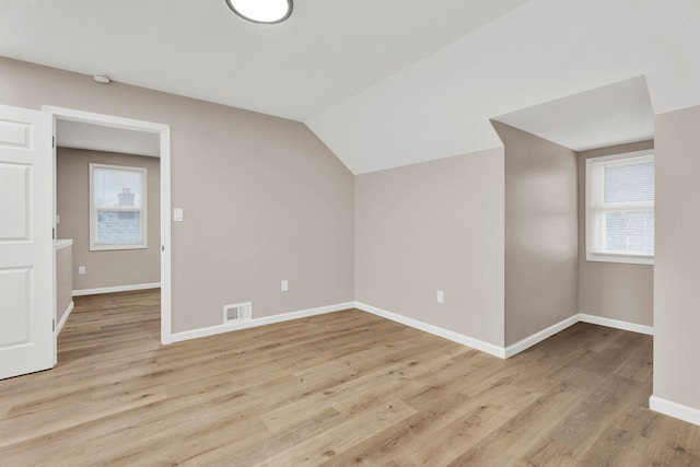 additional living space with lofted ceiling, baseboards, visible vents, and light wood-type flooring