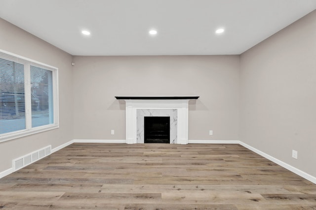 unfurnished living room featuring recessed lighting, wood finished floors, visible vents, and a premium fireplace