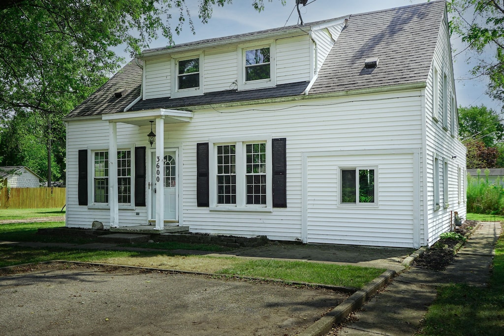 view of front of home with roof with shingles and fence