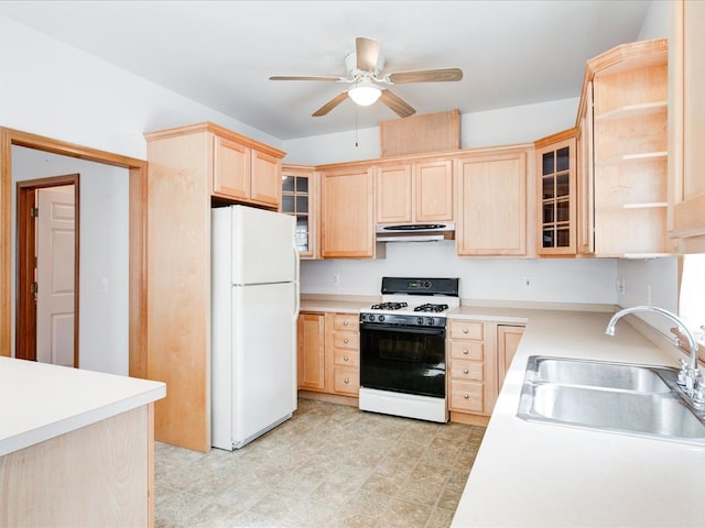 kitchen with light brown cabinetry, a sink, under cabinet range hood, gas range oven, and freestanding refrigerator