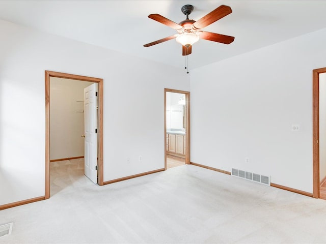 unfurnished bedroom featuring a spacious closet, visible vents, light colored carpet, and baseboards