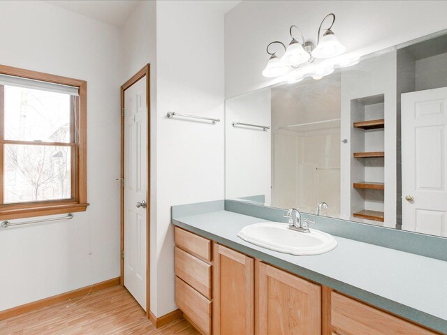 full bath with baseboards, an inviting chandelier, wood finished floors, and vanity