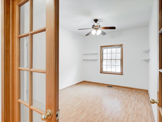 empty room with ceiling fan, visible vents, baseboards, and wood finished floors