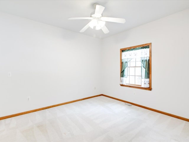 carpeted spare room with visible vents, a ceiling fan, and baseboards