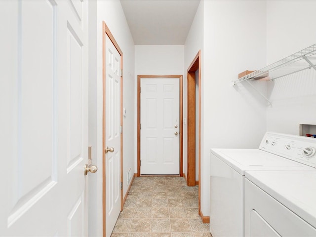 clothes washing area with baseboards, laundry area, and washing machine and clothes dryer