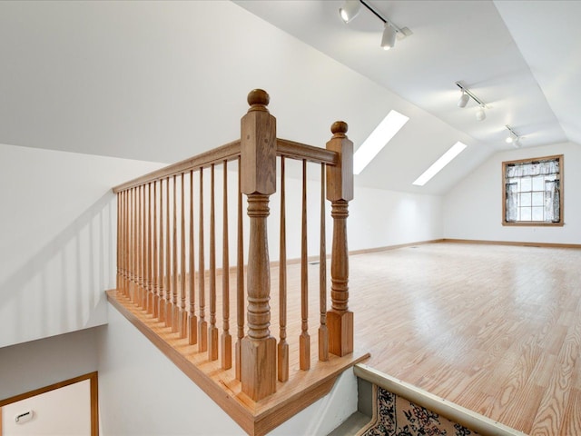 bonus room with baseboards, lofted ceiling with skylight, and wood finished floors