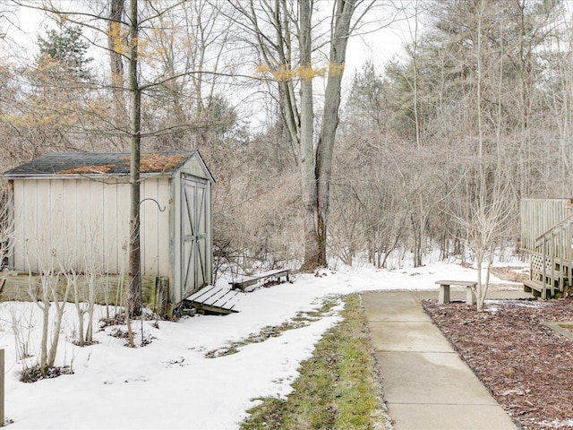 snowy yard featuring an outbuilding and a storage unit