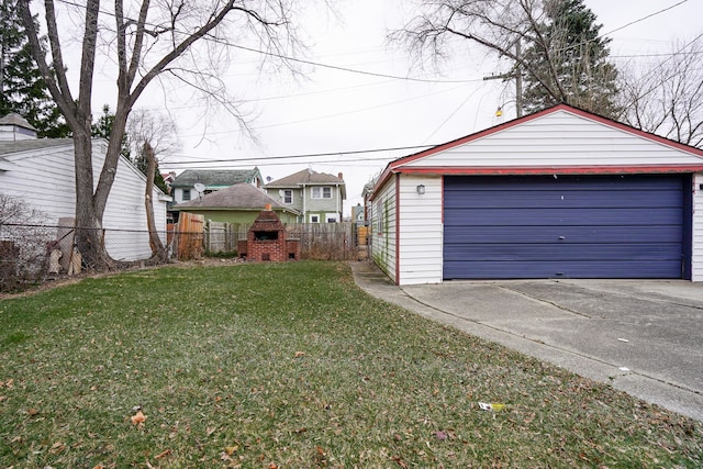 detached garage featuring a fireplace, concrete driveway, and fence