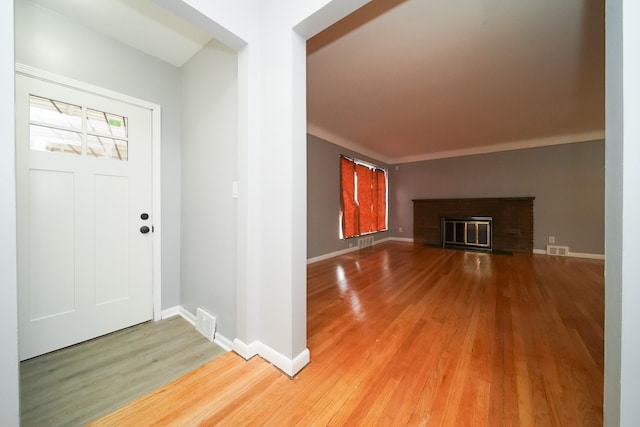 entrance foyer featuring visible vents, baseboards, a fireplace, and light wood finished floors