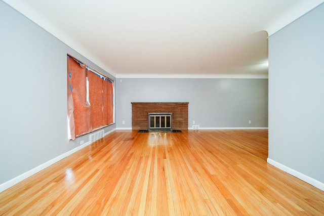 unfurnished living room with a fireplace, light wood-style floors, and baseboards