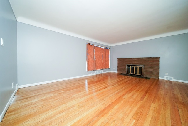 unfurnished living room with a fireplace, visible vents, light wood finished floors, and baseboards