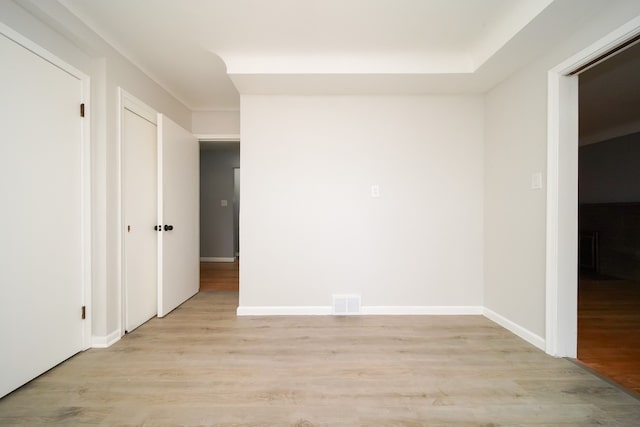 spare room with light wood finished floors, visible vents, and baseboards