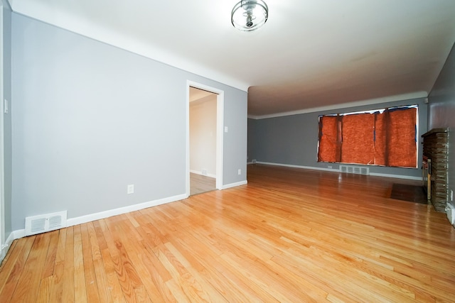 unfurnished room with wood finished floors, visible vents, and baseboards