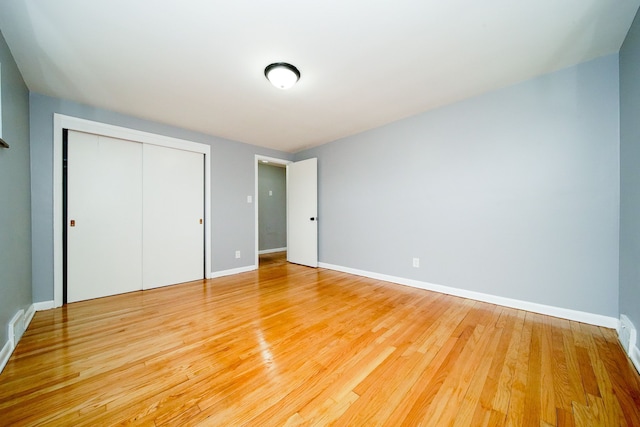 unfurnished bedroom with a closet, baseboards, and light wood finished floors