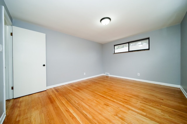 unfurnished room featuring light wood finished floors, visible vents, and baseboards