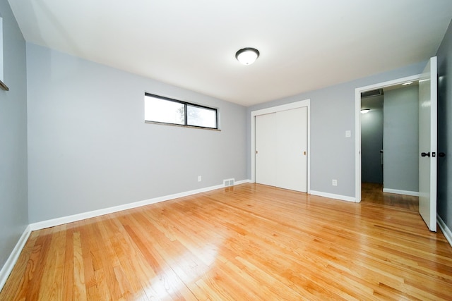 unfurnished bedroom with visible vents, baseboards, a closet, and light wood finished floors