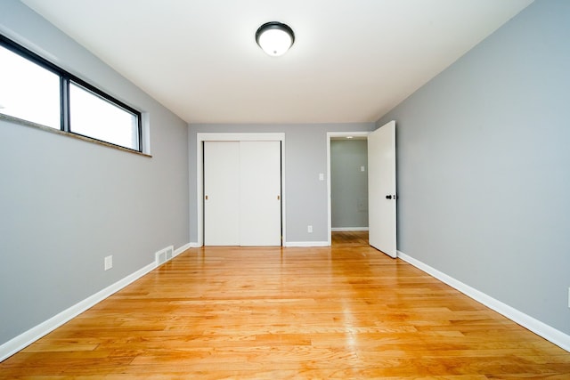 unfurnished bedroom featuring a closet, baseboards, light wood-style floors, and visible vents